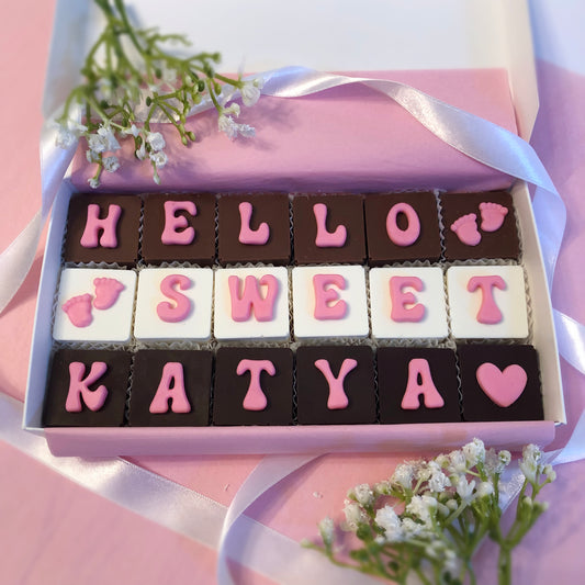 Solid square chocolates with one fondant letter on each, spell out  hello sweet baby with hearts and baby's feet