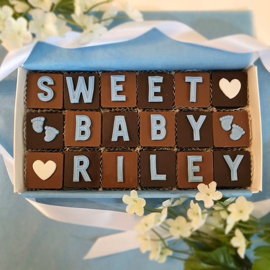 Personalized solid square chocolates with a fondant letter on each spells out sweet baby welcome message